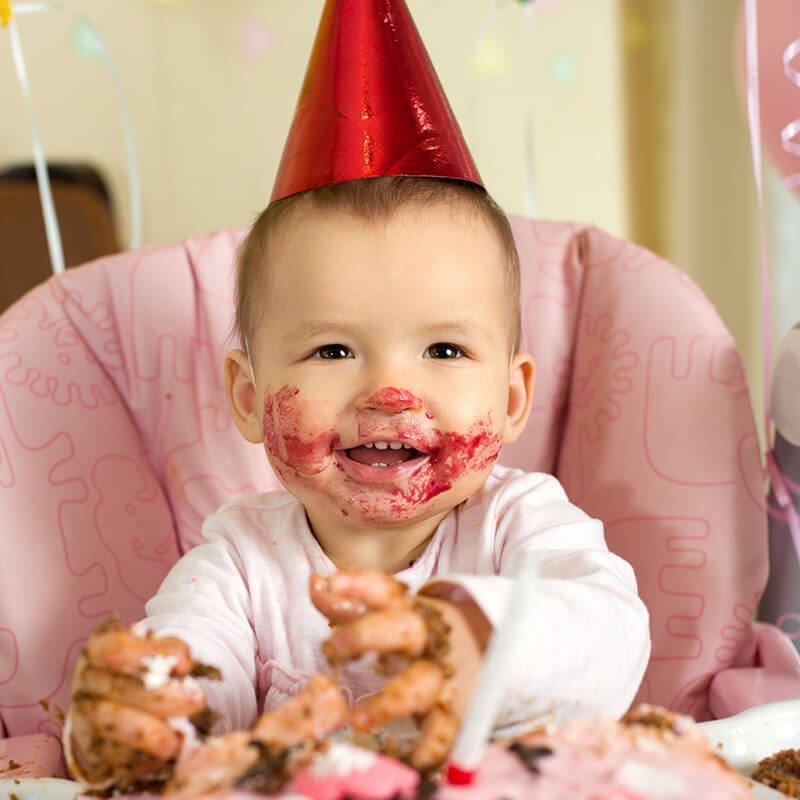 baby eating cake with birthday hat Shutterstock 121983655